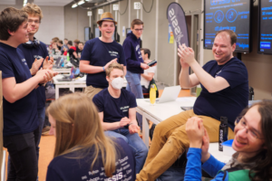 Enkele leden zitten bijeen en en geven applaus voor de net bekendgemaakte winnaar van de ULYSSIS CTF